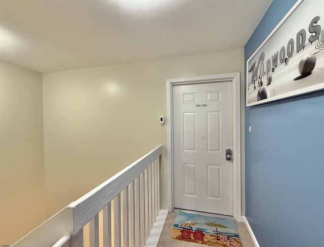 doorway featuring light carpet and baseboards