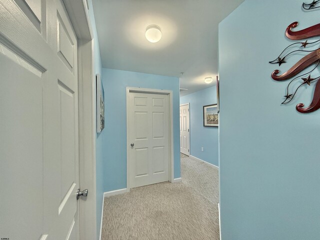 corridor featuring baseboards and carpet floors