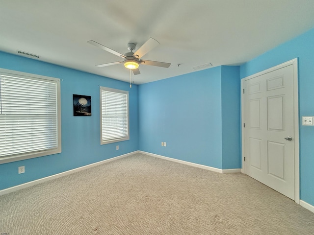 unfurnished room with visible vents, ceiling fan, carpet, and baseboards