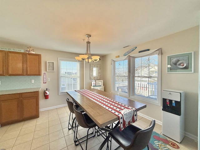 dining space featuring light tile patterned floors, a notable chandelier, and baseboards