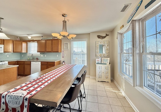 kitchen with baseboards, white appliances, light countertops, visible vents, and brown cabinets