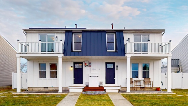 multi unit property with a balcony, crawl space, board and batten siding, a front yard, and fence