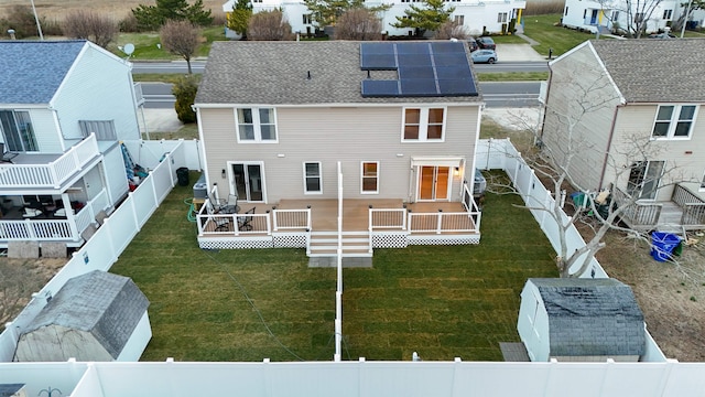 rear view of property featuring roof mounted solar panels, a fenced backyard, a residential view, and a lawn
