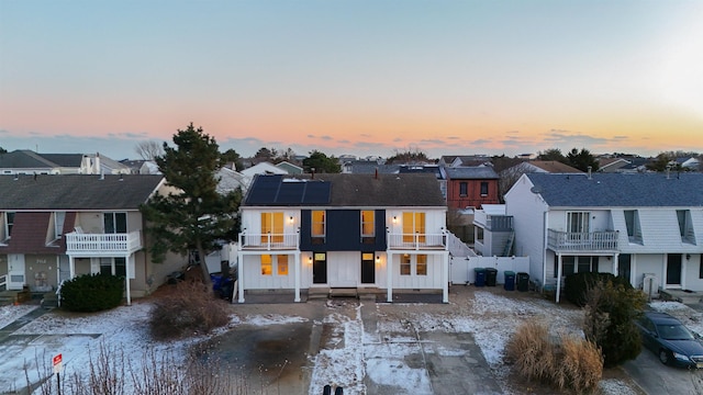view of front of house featuring solar panels, a residential view, and a balcony