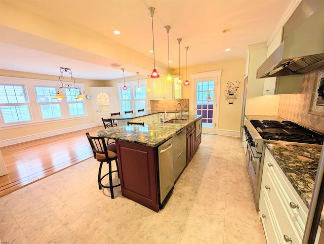 kitchen featuring a sink, stainless steel appliances, backsplash, a breakfast bar area, and extractor fan