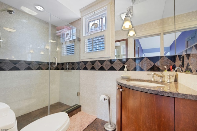 bathroom featuring tile walls, toilet, tiled shower, and vanity