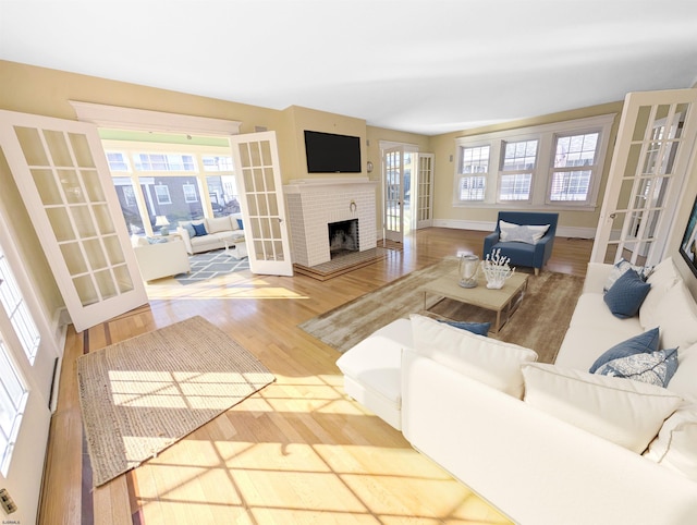 living room with french doors, baseboards, wood finished floors, and a fireplace