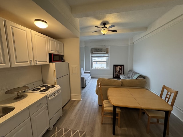 kitchen featuring baseboards, white appliances, white cabinets, ceiling fan, and wood finished floors