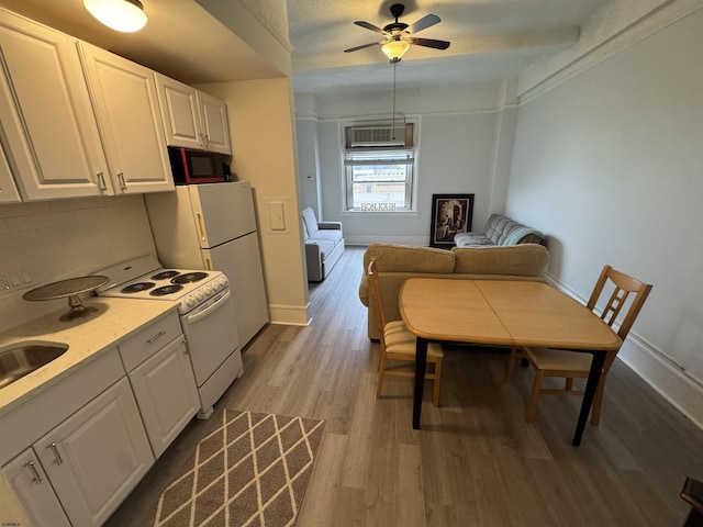kitchen featuring black microwave, light countertops, white cabinets, electric stove, and wood finished floors