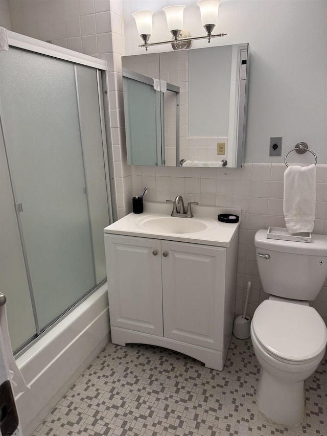 bathroom with toilet, tile patterned floors, vanity, and tile walls