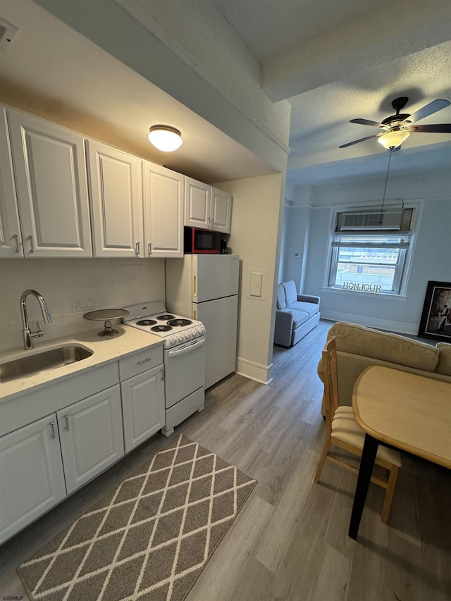 kitchen with open floor plan, white cabinetry, a sink, and white appliances