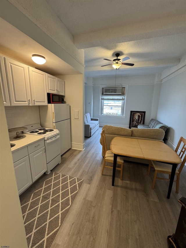 kitchen with white range with electric stovetop, open floor plan, black microwave, white cabinetry, and wood finished floors