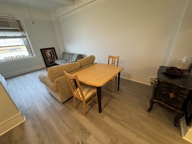 living room with baseboards, light wood-type flooring, and a wall unit AC