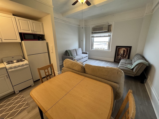 living room featuring baseboards, ceiling fan, wood finished floors, and a wall mounted air conditioner