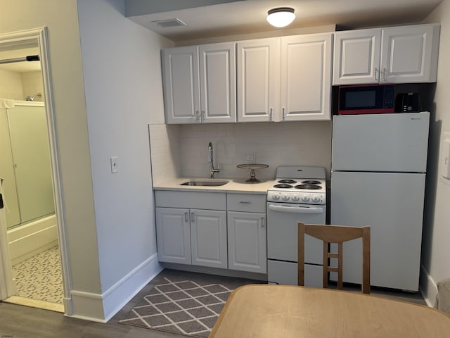 kitchen with a sink, light countertops, white appliances, white cabinetry, and decorative backsplash