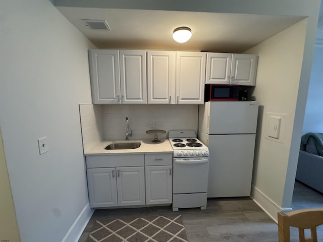 kitchen with white appliances, dark wood-style floors, light countertops, backsplash, and a sink