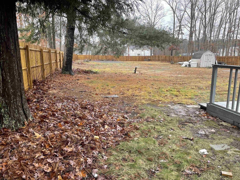 view of yard with a fenced backyard, an outdoor structure, and a storage shed