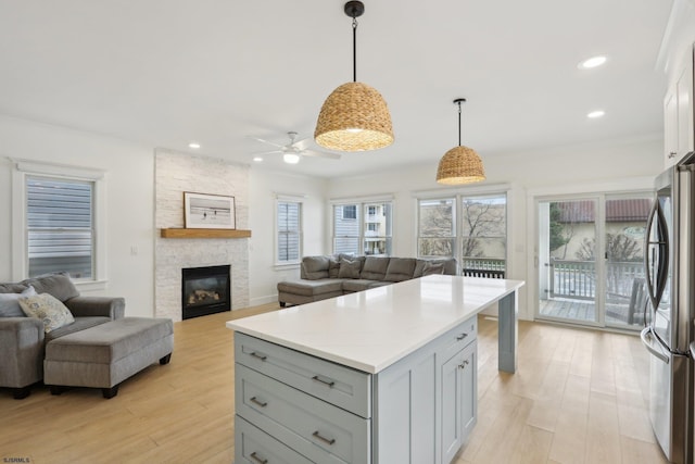 kitchen with light countertops, freestanding refrigerator, light wood-style flooring, open floor plan, and ceiling fan