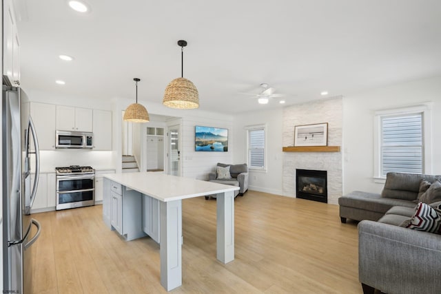 kitchen with stainless steel appliances, light countertops, open floor plan, and ceiling fan