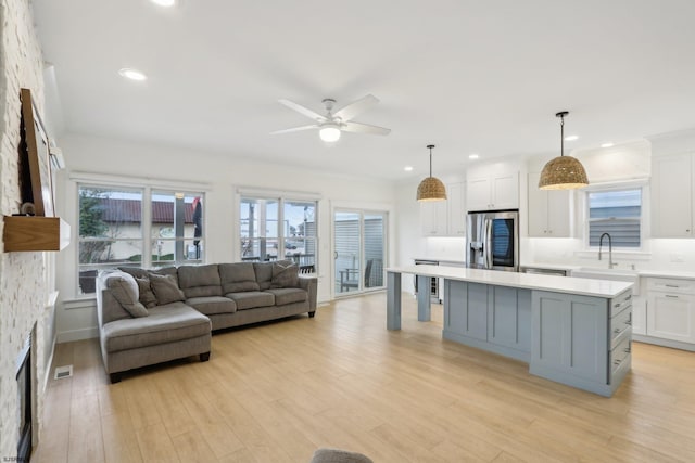 kitchen with white cabinets, light countertops, a sink, a kitchen island, and stainless steel fridge