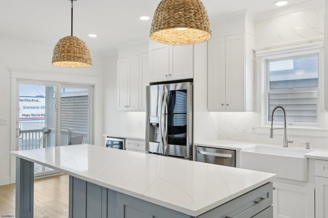 kitchen featuring plenty of natural light, light stone countertops, stainless steel appliances, and a sink