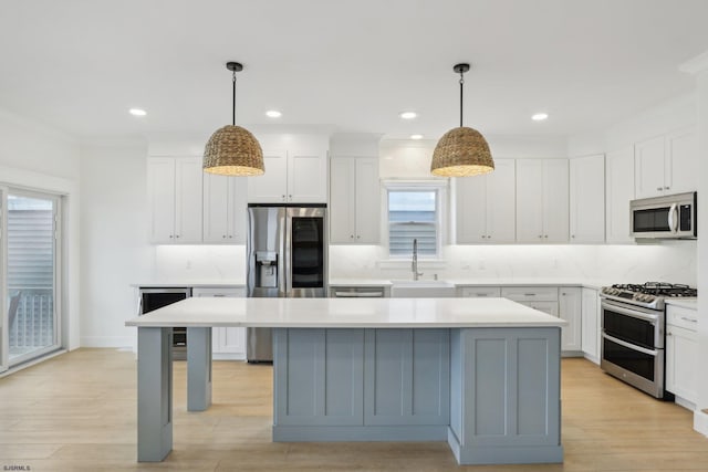 kitchen featuring a center island, tasteful backsplash, a sink, light countertops, and appliances with stainless steel finishes