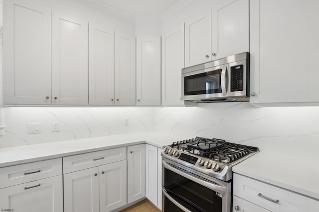kitchen with white cabinets, light stone countertops, decorative backsplash, and stainless steel appliances