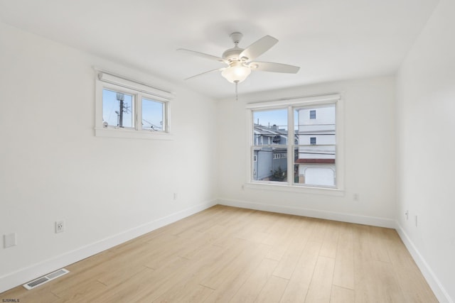 unfurnished room featuring light wood-type flooring, visible vents, baseboards, and a healthy amount of sunlight