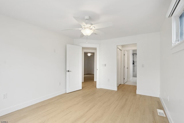 empty room with light wood-style flooring, visible vents, a ceiling fan, and baseboards