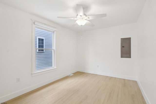 unfurnished room featuring light wood-type flooring, electric panel, a ceiling fan, and baseboards