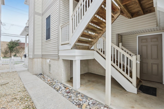 view of property exterior featuring fence and stairs