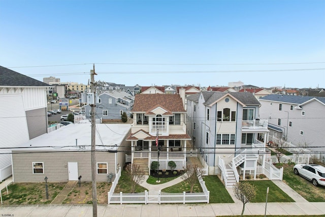 view of front of home with a residential view, fence private yard, and a balcony
