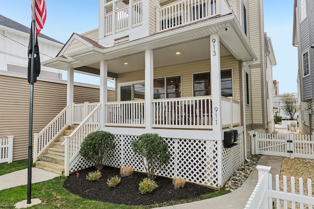 view of front of property with fence, covered porch, a balcony, and a gate