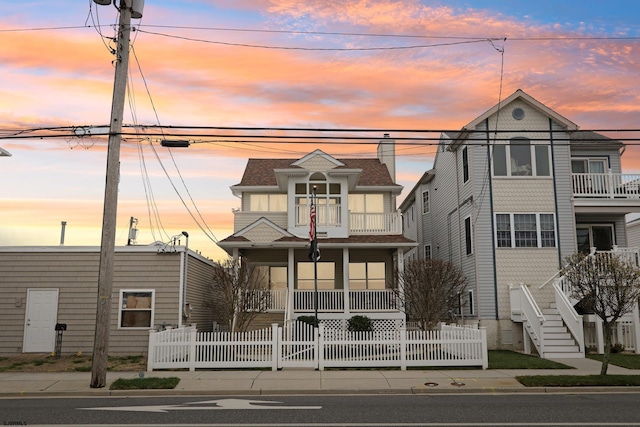 view of front of house with stairway, fence, a balcony, a porch, and roof with shingles