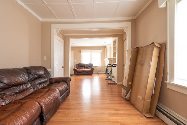 living room with a baseboard heating unit, ornamental molding, and light wood-type flooring