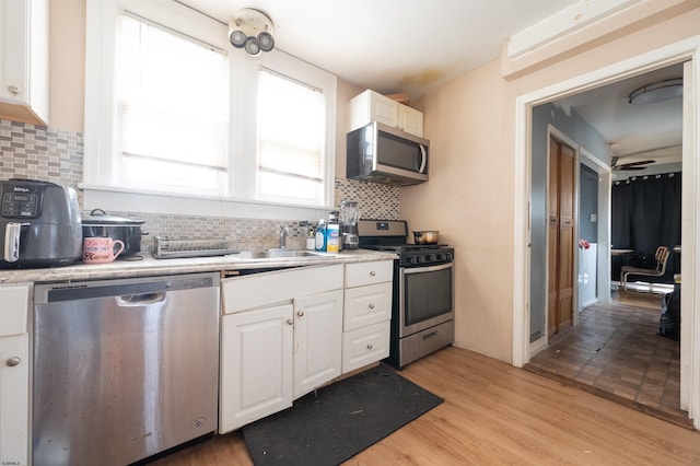 kitchen featuring white cabinets, a sink, a ceiling fan, light countertops, and appliances with stainless steel finishes