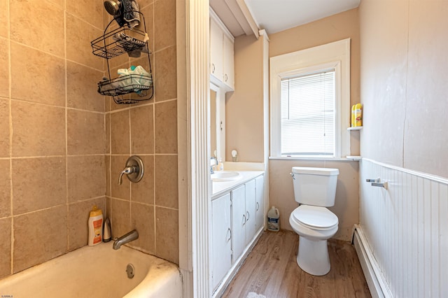 bathroom featuring  shower combination, toilet, wood finished floors, vanity, and a baseboard radiator