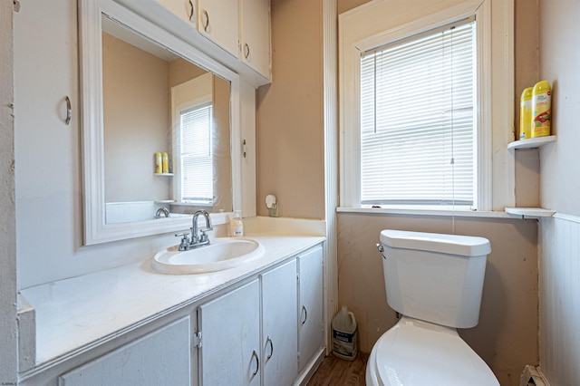 half bathroom featuring a baseboard radiator, toilet, vanity, and wood finished floors