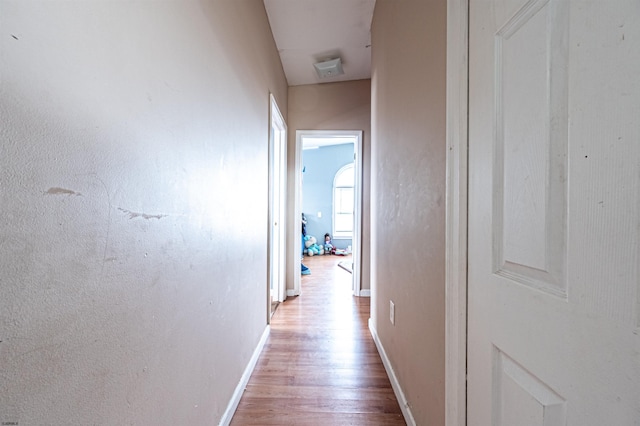 corridor featuring baseboards and wood finished floors