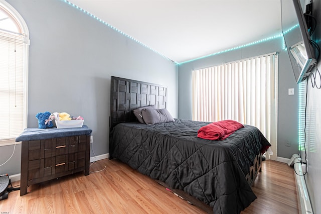 bedroom with lofted ceiling, baseboards, and light wood-style flooring