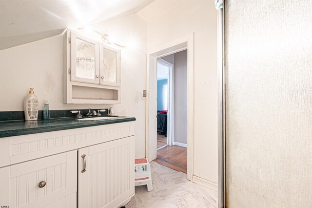bathroom featuring vaulted ceiling, marble finish floor, and vanity