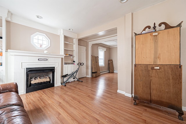 living room featuring baseboards, light wood-style flooring, built in features, and a fireplace