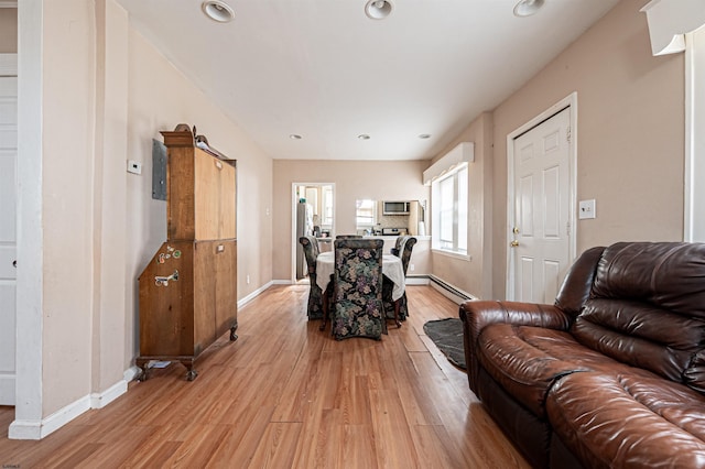 living room with baseboard heating, baseboards, recessed lighting, and light wood-style flooring