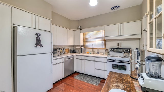 kitchen with white cabinetry, dark wood-style floors, a sink, and white appliances