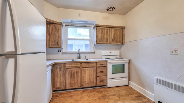 kitchen featuring brown cabinets, light countertops, a sink, and white appliances