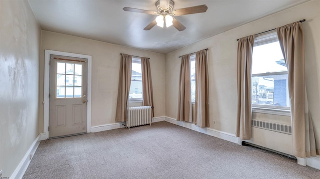 interior space with radiator heating unit, carpet floors, baseboards, and ceiling fan