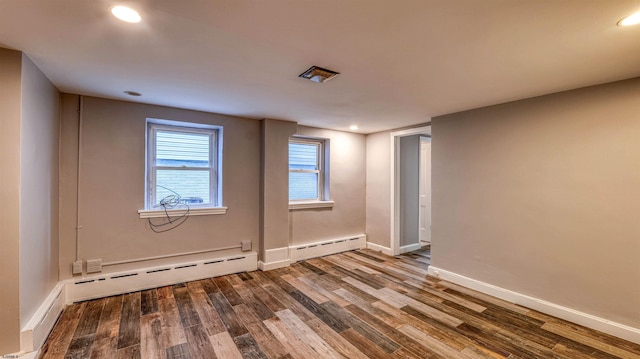 spare room with a baseboard radiator, wood finished floors, baseboards, and recessed lighting