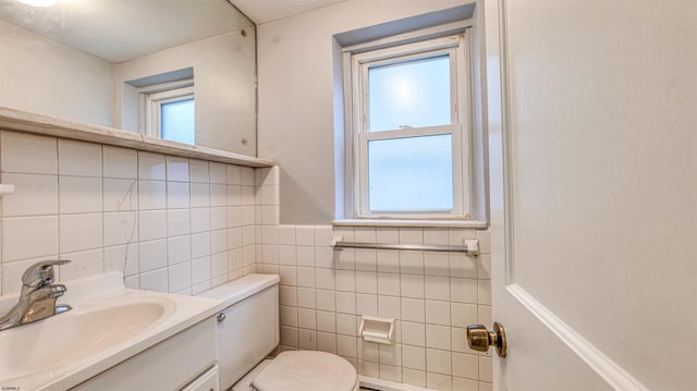 half bathroom featuring tile walls, a healthy amount of sunlight, vanity, and toilet