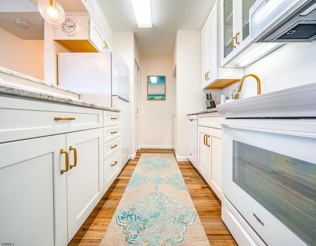 kitchen with stove, white cabinets, exhaust hood, and freestanding refrigerator