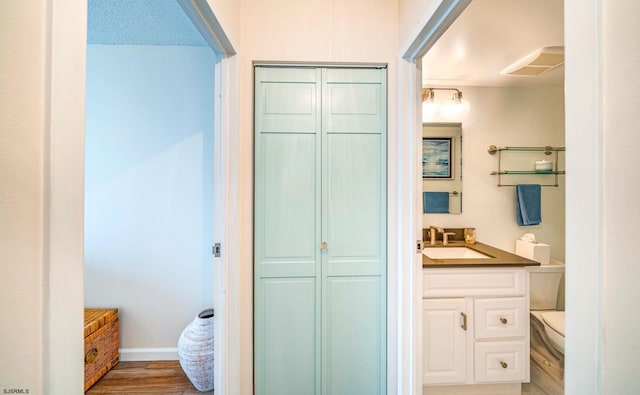 bathroom featuring vanity, a closet, toilet, baseboards, and wood finished floors